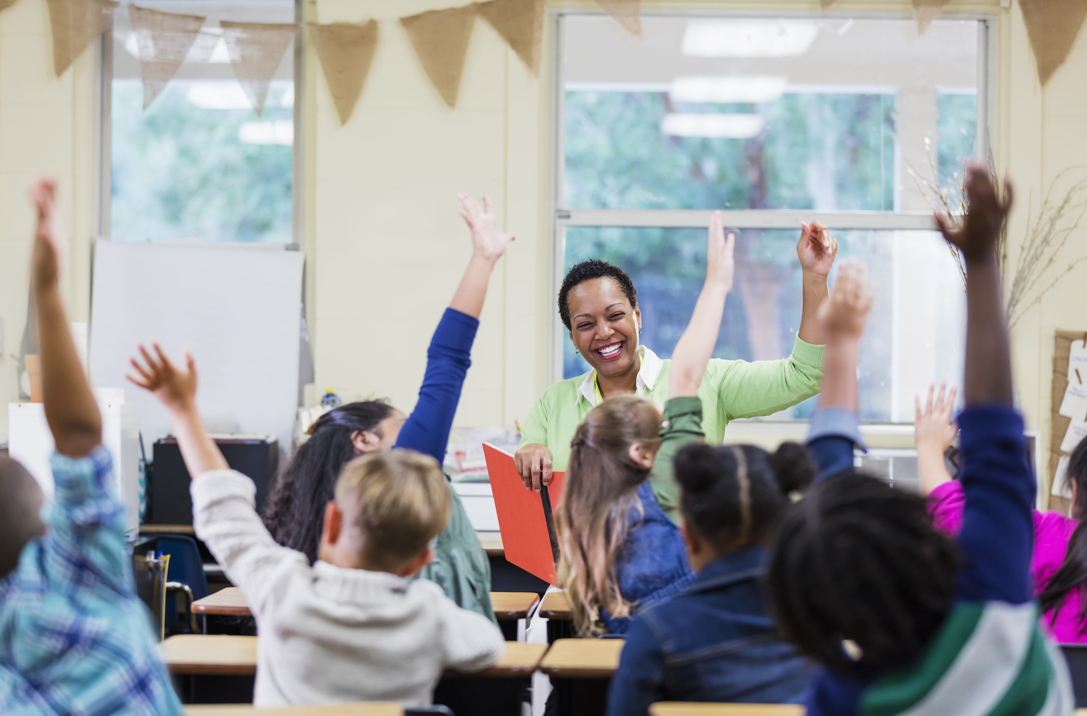 School children raising their hands to answer a teacher's question School children raising their hands to answer a teacher's question